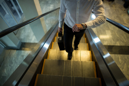 Commuter checking time while walking on escalator
