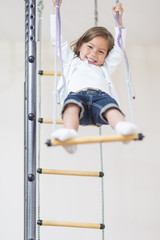 Children Activity Concepts.Happy Smiling Little Caucasian Girl Having Exercises on Wall Bars Indoors.