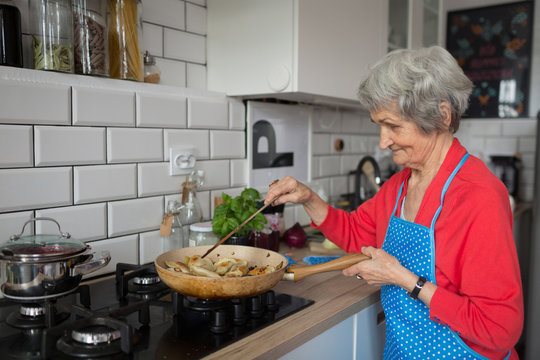 Senior woman cooking food in kitchen