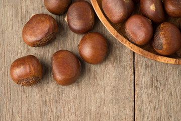 Ripe chestnuts in wooden bowl  on woden table.