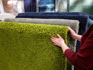 Woman choosing carpet in the store, closeup
