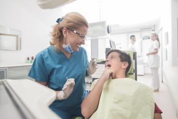 Fototapeta premium Boy with perfect teeth at the dentist doing check up with the clinic at the background - oral hygiene health care concept