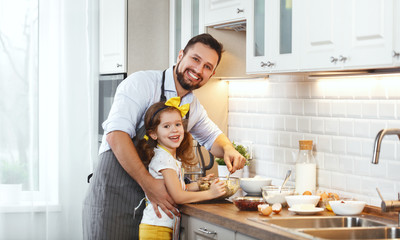 happy family in kitchen. Father and child daughter knead dough and bake biscuits .