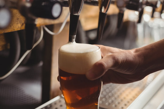 Close Up Of Bar Tender's Hand Filling Beer In Beer Glass