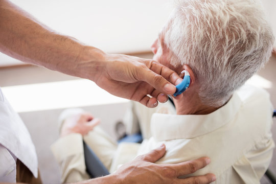 Nurse giving hearing device to a senior man