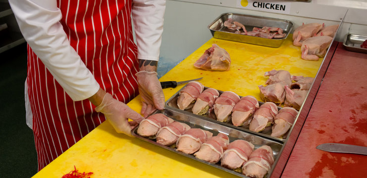 Mid section of butcher holding a tray of chicken and steak rolls