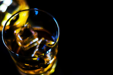 Scottish whiskey in a glass with ice cubes, golden color whiskey