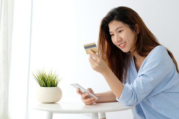 Young asian woman holding credit card and using smart phone for shopping online, business and technology concept, online payment, digital money