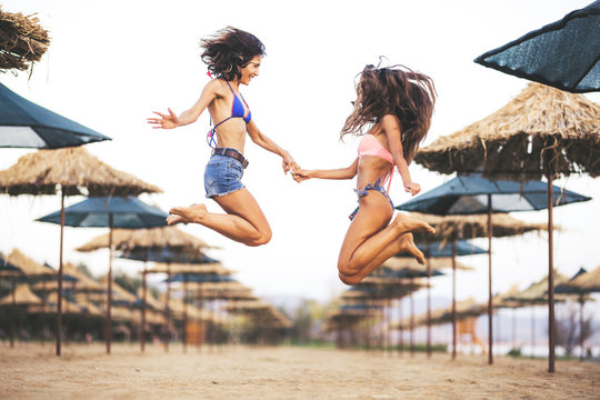two sexy girls jumping on a beach