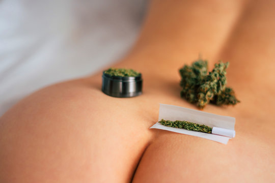 The concept of sex and marijuana. themed weed and sex. joint weed Cannabis buds on the girl's ass grinder rolled marijuana
