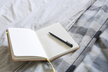 Home office in a cozy bed. Detail of a note book and a pen.