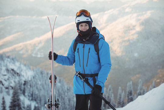 Portrait of man standing with ski outdoors