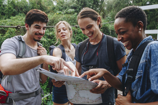 Group Of Friends Looking At A Map Together Travel And Teamwork Concept