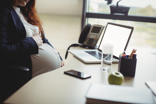 Pregnant businesswoman touching her belly