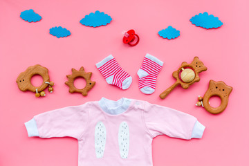 Baby shower concept. Baby's clothes and toys on pink background top view