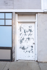 Fototapeta premium A weathered door next to a facade on an empty storefront in Anniston, Alabama, USA