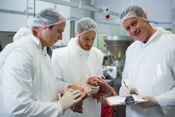 Butchers maintaining records on clipboard