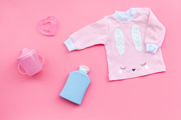 Child birth concept. Clothes and accessories for newborn on pink background top view copy space