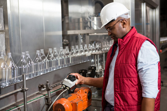 Male employee operating machine in juice factory