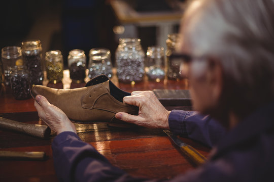 Senior cobbler examining shoe in workshop