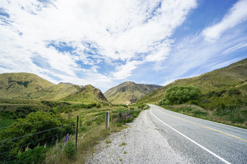 concrete road along green hill range in New Zealand in spring season