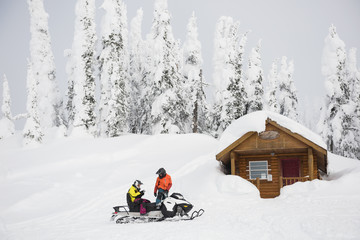 Couple riding snowmobile in snowy alps