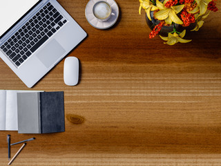 Top view of wooden table in office with laptop and coffee cup.