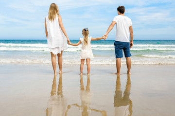 Rear view of a young happy family on tropical beach.