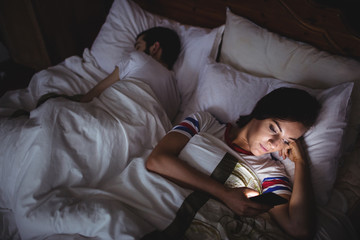 Woman using mobile phone while lying on bed