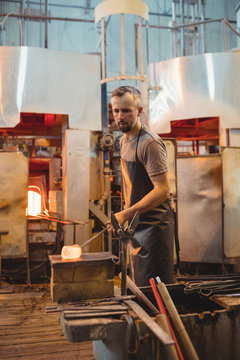 Glassblower shaping a molten glass on marver table
