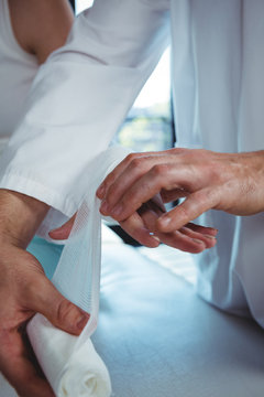 Male therapist putting bandage on female patient hand