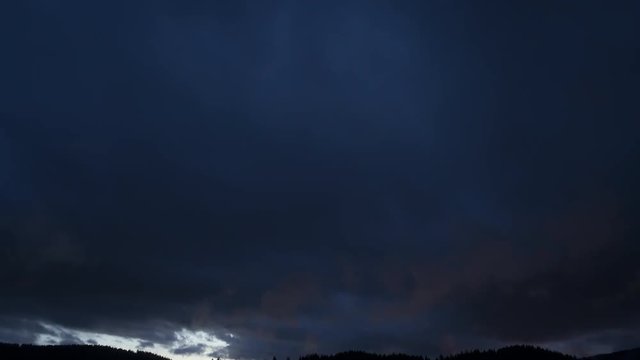 4K Time-Lapse. Impresionante atardecer. Paso de d&iacute;a a noche. Densas nubes pasando sobre una monta&ntilde;a. La luz rojiza del sol se refleja en ellas. Impresionante anochecer con mucha fuerza. Alemania
