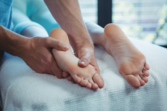 Male physiotherapist giving foot massage to female patient