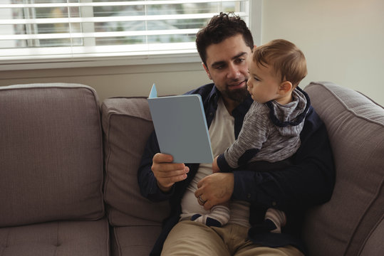 Father reading a book while holding his baby