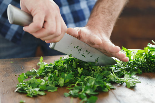 Close up male hands chopping fresh parsley