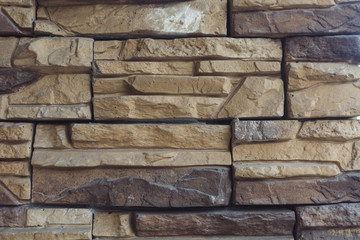 Unusual designer brick wall of cream color made of bricks of different shapes and shades. Background image of beautiful interior wall. Exterior from varicolored stones.