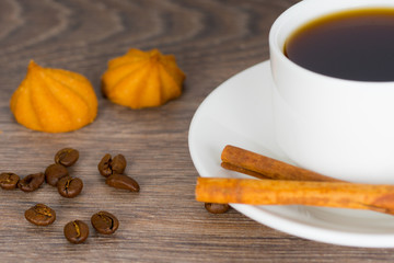 black coffee cup with beans and cookies and cinnamon sticks