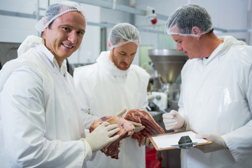 Butchers maintaining records on clipboard