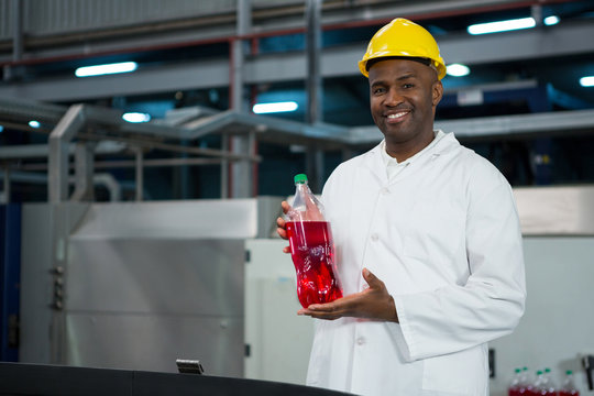 Male worker showing juice bottle in factory