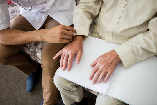 Blind senior man using braille to read