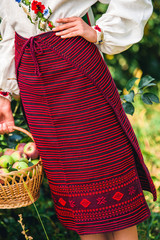 girl is standing in an embroidered red striped skirt in the garden