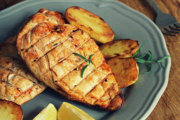 Grilled chicken breast with fried potato and lemon