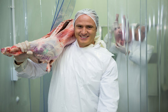 Portrait of butcher carrying raw meat