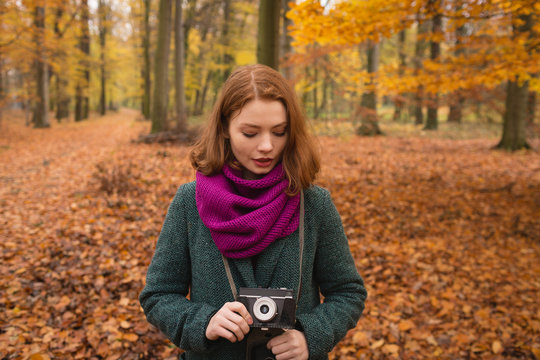 Young woman with camera standing outdoors