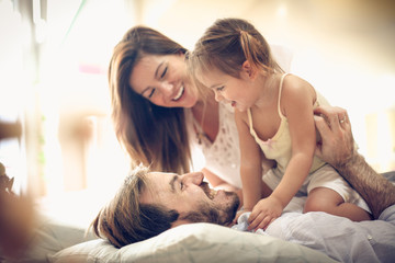 Playful family in bed.