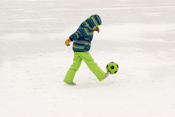 A young lady in a blue ski suit plays football with children in the snow. Yellow sled, sunglasses,...