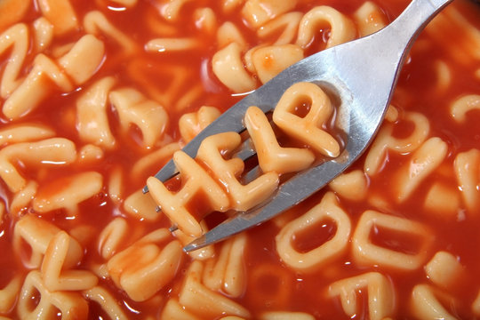 Spaghetti letter spelling the word help with the letters held up on a fork.
