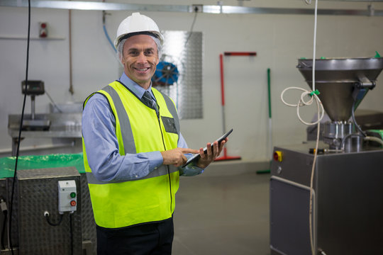 Smiling technician with digital tablet at meat factory