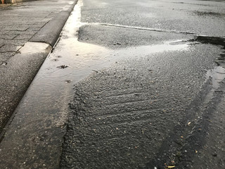 Pfütze auf einer asphaltierten Straße mit hineinfallenden Regentropfen