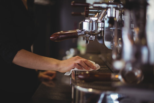 Close up of man cleaning coffee machine in cafe